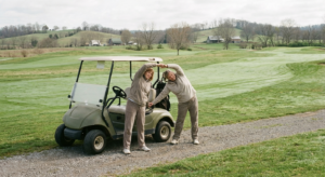Man and woman stretching on a golf course before activity to prevent spring back pain flare-ups